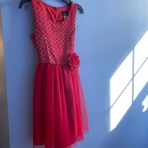 A red Christmas dress with silver lacing on the top and a red flower on the hip